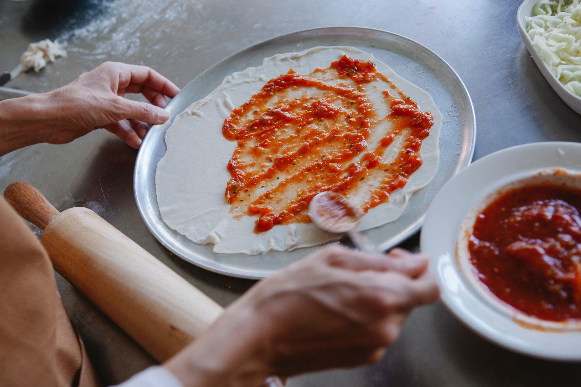 Rozsmarowywanie sosu pomidorowego na cieście na domową pizzę